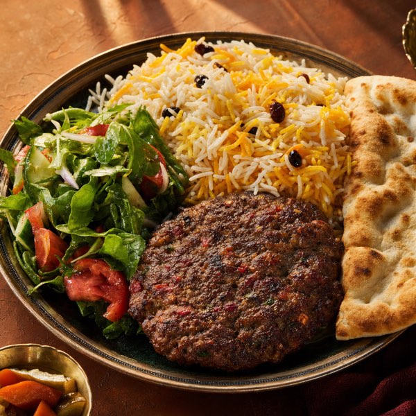 A Silk Road lunch plate — Chapli Kabob with rice, Afghan salad, and fresh tandoor bread